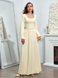 Full-body view of a woman in a pale yellow maxi dress with a square neckline and long sleeves.