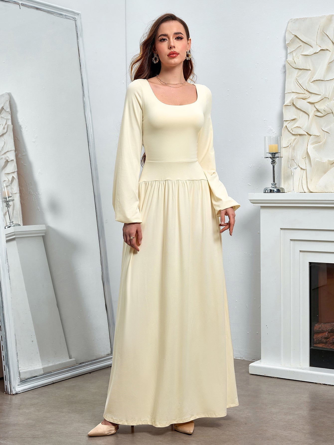 Full-body view of a woman in a pale yellow maxi dress with a square neckline and long sleeves.