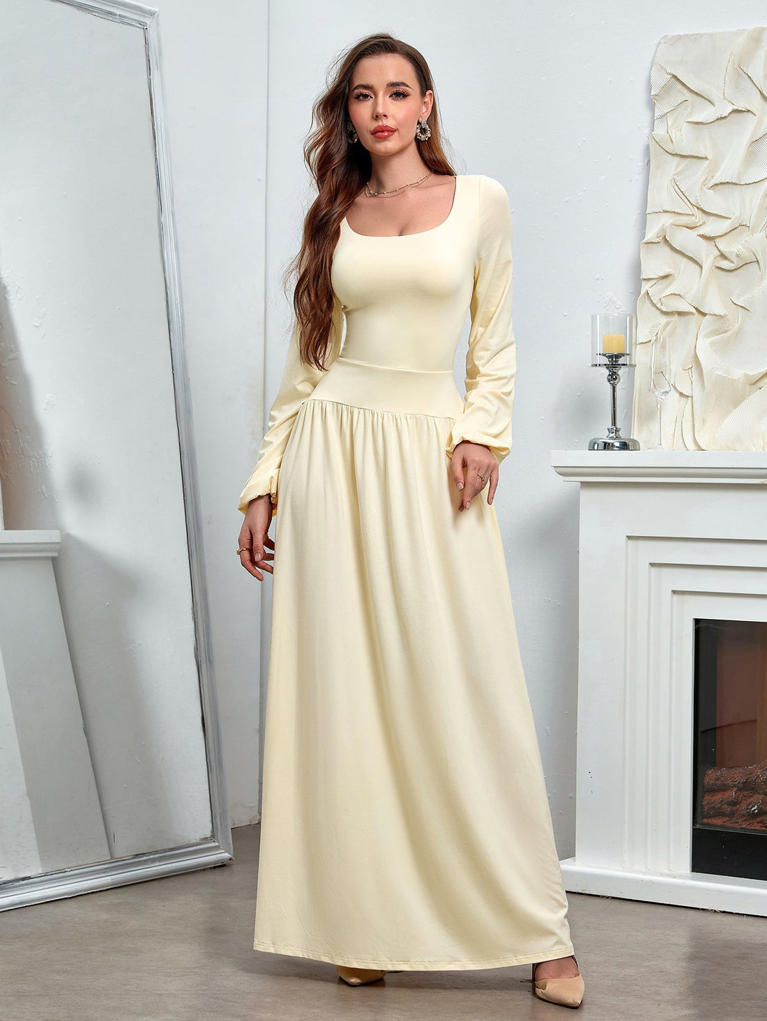Woman wearing a long-sleeved, pale yellow maxi dress with a square neckline and gathered waist.