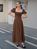 Woman posing in a brown puff sleeve midi dress with a high slit