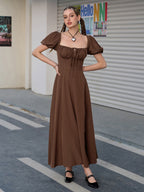Woman posing in a brown puff sleeve midi dress with a high slit