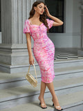 Model posing in a pink floral ruched midi dress with tie-front detail.