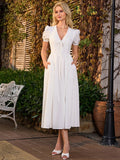 Woman wearing a white midi dress with puff sleeves and a cinched waist, standing outdoors.