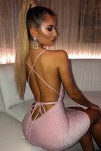 Woman in a champagne sparkly bodycon mini dress with spaghetti straps and a backless tie-back detail, viewed from the side.