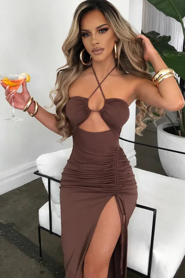 Model wearing a brown ruched halter neck maxi dress with a cut-out detail and high slit. Main image