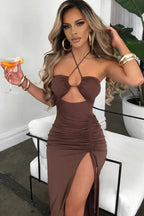 Model wearing a brown ruched halter neck maxi dress with a cut-out detail and high slit.