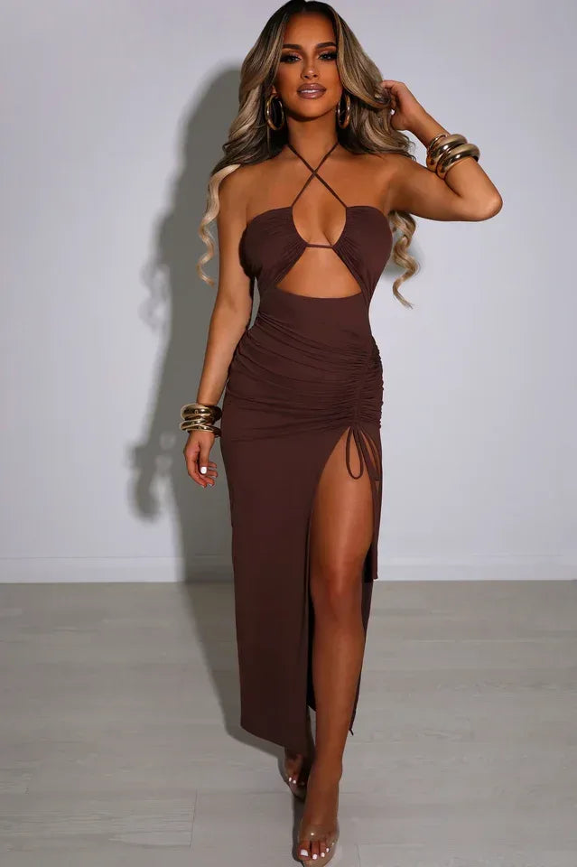 Full body shot of a woman in a brown halter neck maxi dress with a cut-out and ruched detailing.