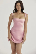 Close-up of a woman wearing a pink satin mini dress with spaghetti straps and a sweetheart neckline.