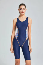 woman modeling a navy blue athletic swimsuit with a racerback and geometric side accents