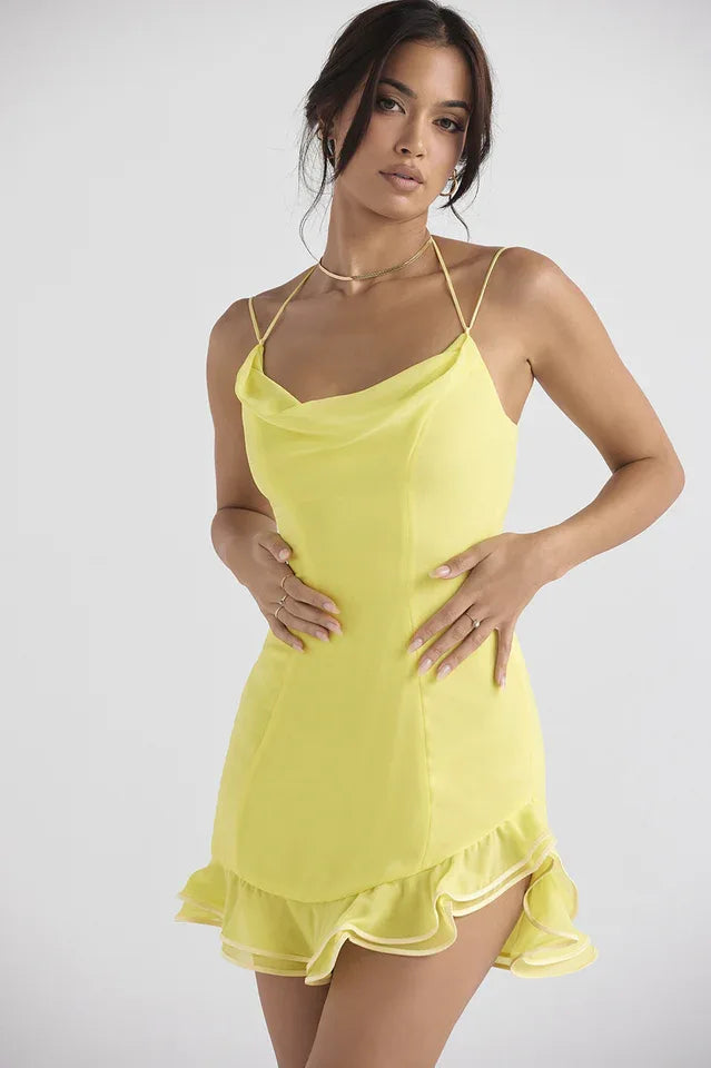 Front view of a woman in a yellow satin cowl neck mini dress with spaghetti straps.