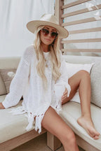 Woman in a white knit tunic and hat sitting on a couch
