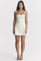 Side view of a model in a cream white duchess satin mini dress, showcasing the silhouette.