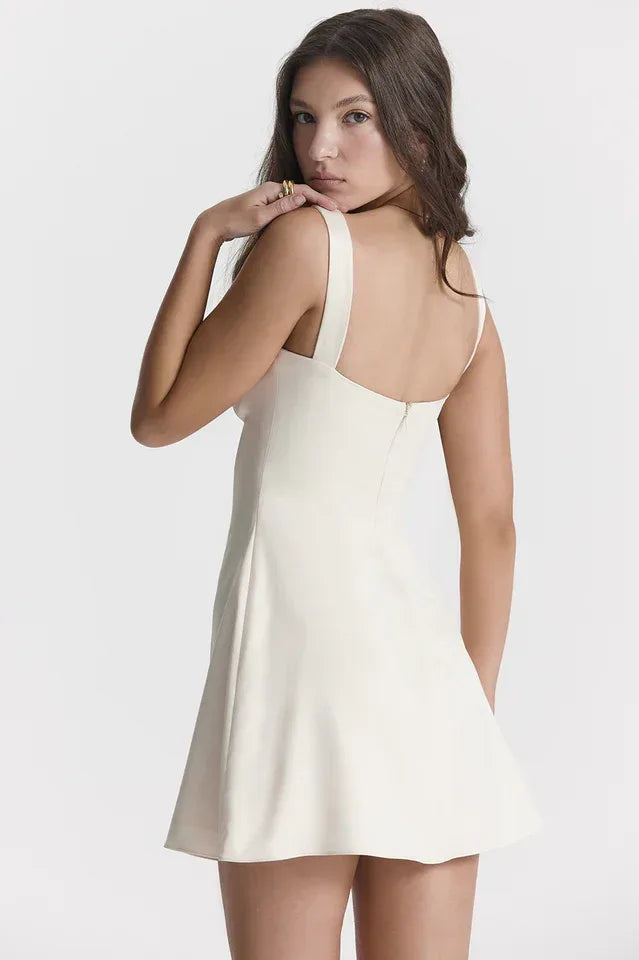 Model wearing a cream white duchess satin mini dress with wide straps and a square neckline, back view showing zipper.