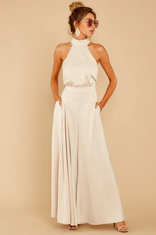 woman wearing a light beige halter neck satin jumpsuit with wide leg pants and pockets Main image