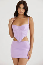 Front view of a woman in a lavender faux leather corset top paired with a matching mini skirt.