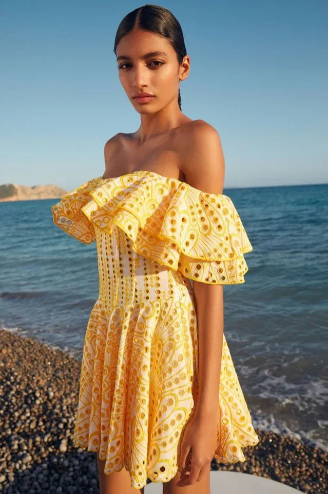Woman wearing a yellow Bardot embroidered dress on a beach Main image