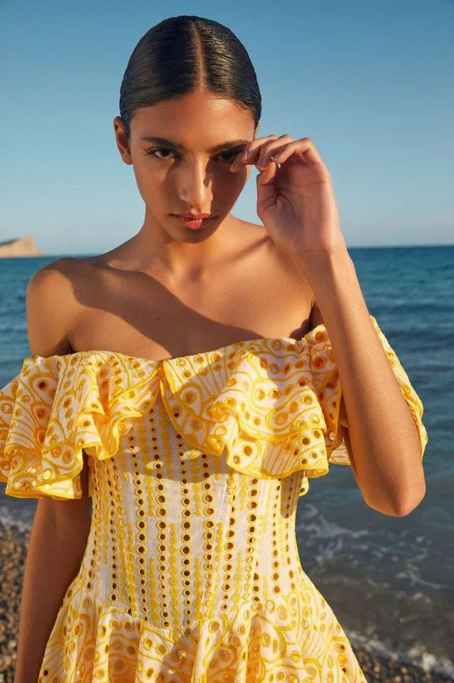 Model posing in a yellow Bardot embroidered dress