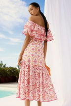 Woman wearing a white and pink off-the-shoulder midi dress with ruffle trim and embroidered circular patterns, viewed from the back.