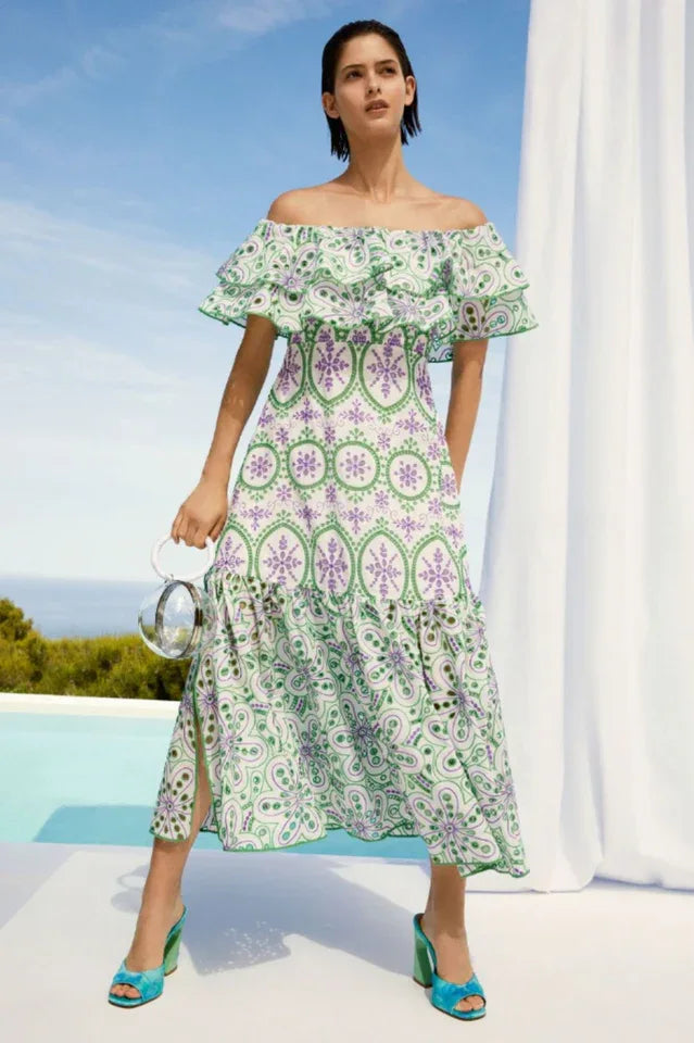 Woman wearing a white and green off-the-shoulder midi dress with ruffle trim and embroidered circular patterns. Main image