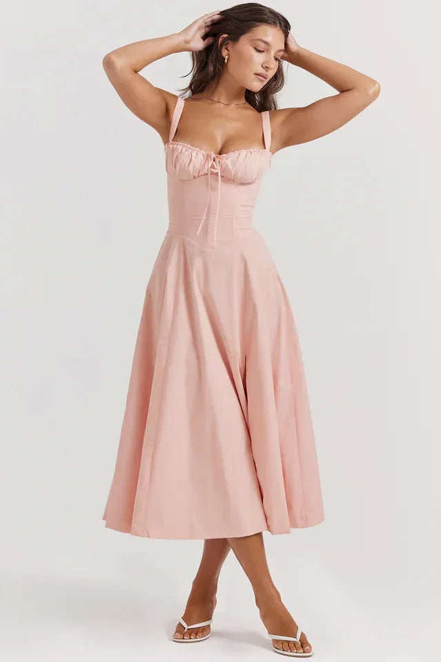 Woman in a pink cotton poplin midi dress posing with hands on her head, highlighting the dress's design.