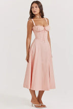Side profile of a woman in a pink cotton poplin midi dress, showcasing the fit and flare silhouette.