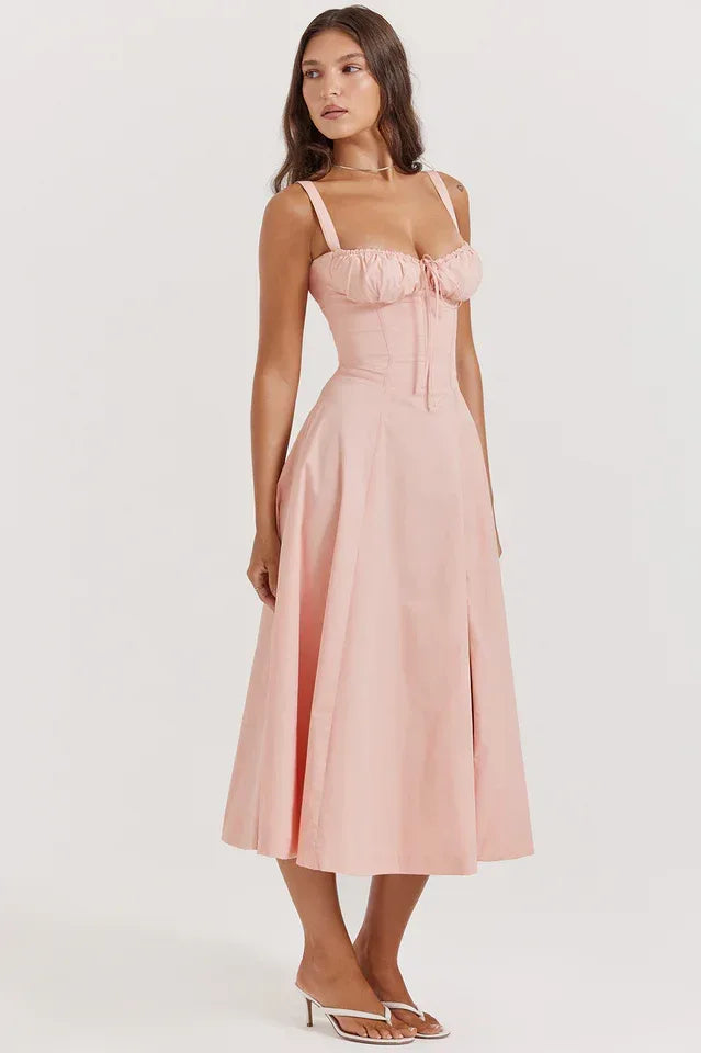 Side profile of a woman in a pink cotton poplin midi dress, showcasing the fit and flare silhouette.
