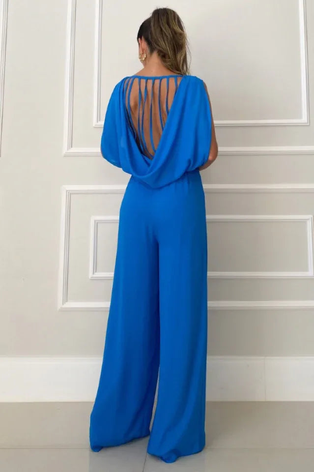 back view of a woman in a royal blue wide leg jumpsuit with an open back featuring multiple straps
