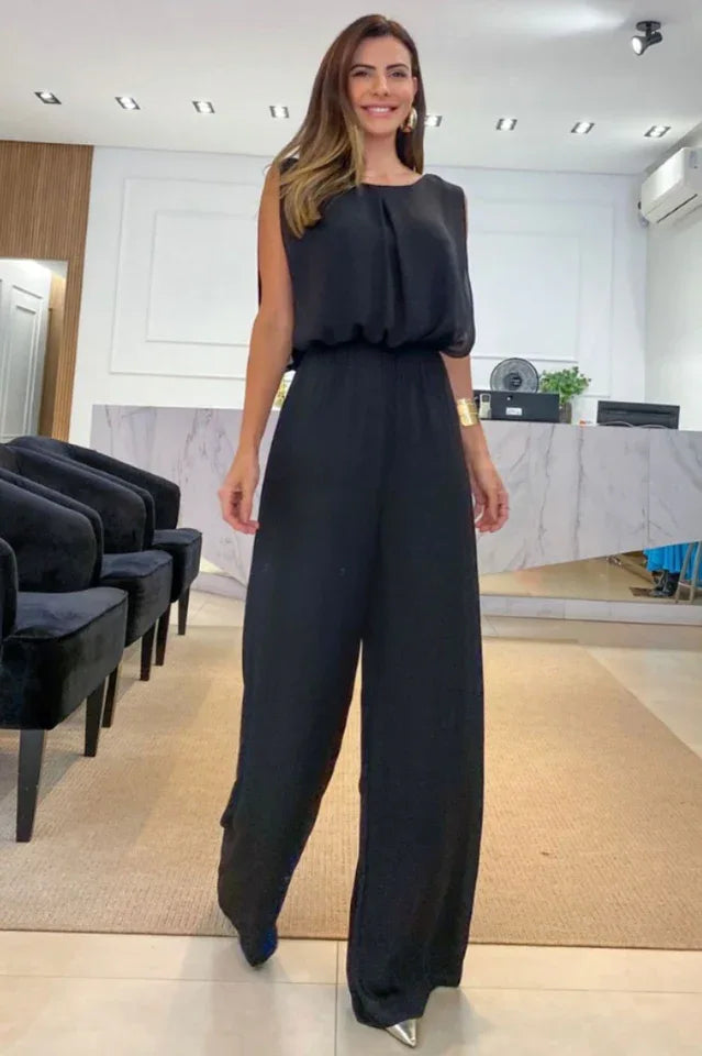 woman wearing a black wide leg jumpsuit with a round neck and elasticated waist