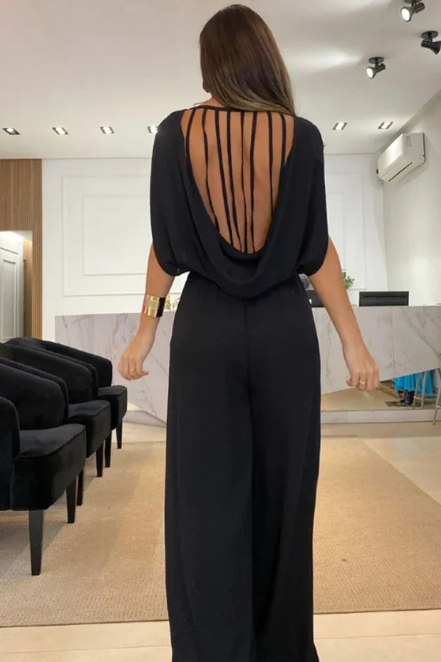 back view of a woman in a black wide leg jumpsuit with an open back and strappy detail