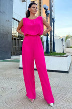 woman wearing a hot pink wide leg jumpsuit with a round neck and sleeveless design