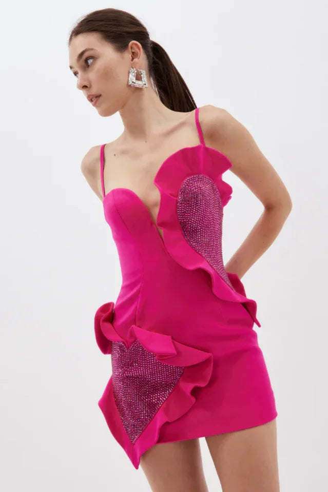 Woman wearing a hot pink mini dress with asymmetrical ruffle detailing and crystal-embellished panels