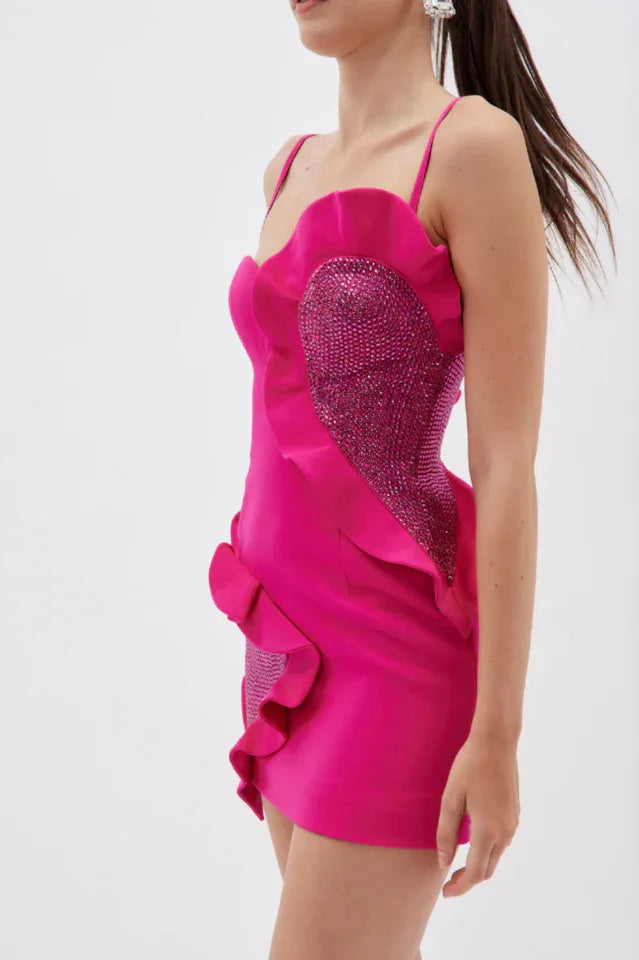 Side view of a woman in a hot pink mini dress showcasing its fitted silhouette and embellishments