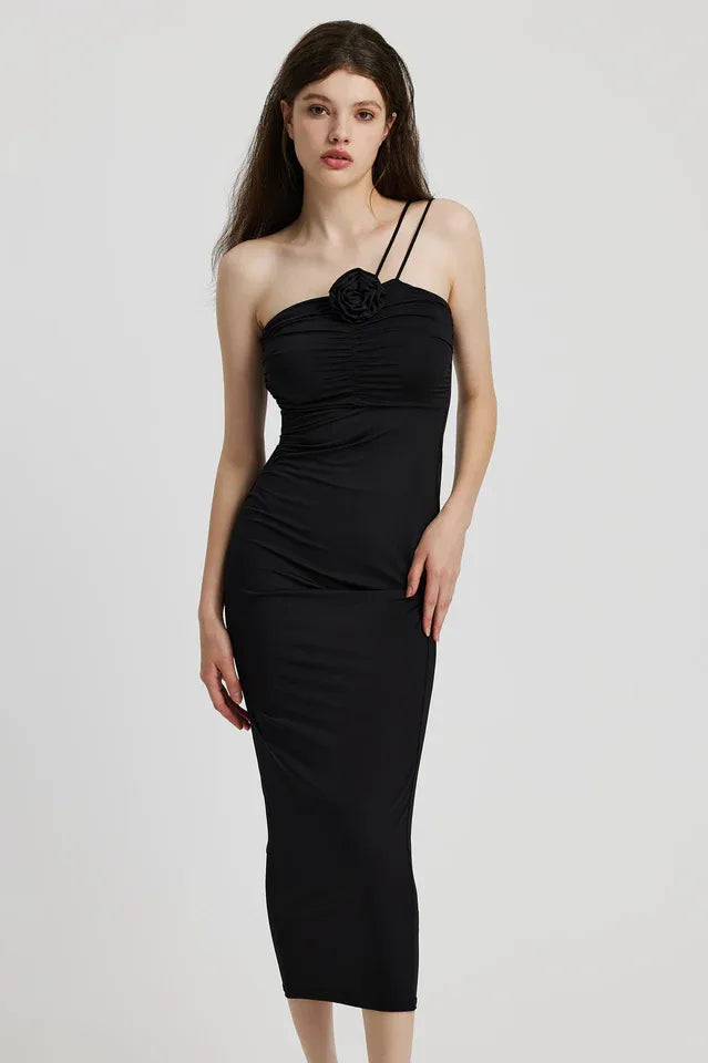 Woman wearing a black ruched one-shoulder maxi dress with a floral applique