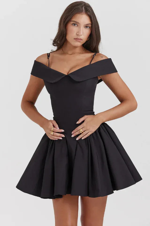 Woman wearing a black off-the-shoulder mini dress with a pleated skirt. Main image