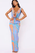 Woman wearing a blue, orange, and white tie-dye print maxi dress with a deep V-neck and sleeveless design.