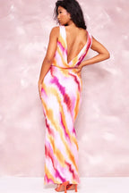 Back view of a woman wearing a pink, orange, and purple tie-dye print maxi dress with a deep V-back.
