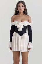 Woman wearing an off-the-shoulder black and cream mini dress with a bow detail
