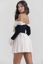 Rear view of a woman in a black and cream off-the-shoulder mini dress