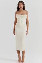 Full-length view of a woman in a white satin strapless corset midi dress.