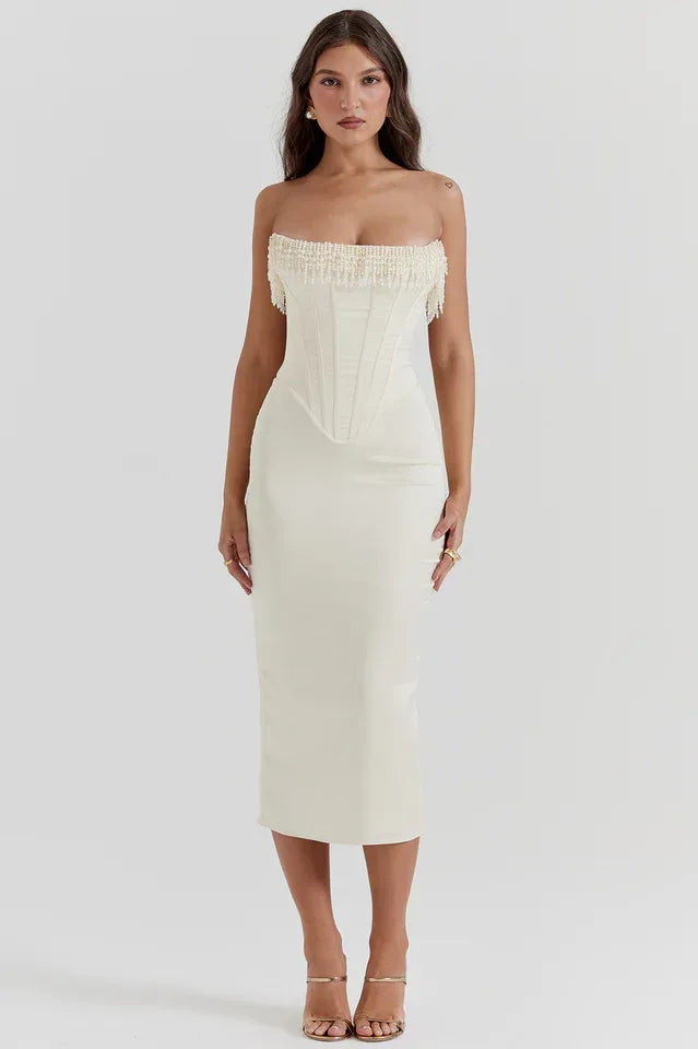 Full-length view of a woman in a white satin strapless corset midi dress.