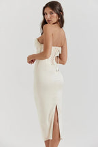 Back view of a white satin strapless corset midi dress with lace-up detail and slit hem.