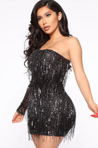 Close-up of a woman wearing a black sequined one-shoulder mini dress with fringe detail
