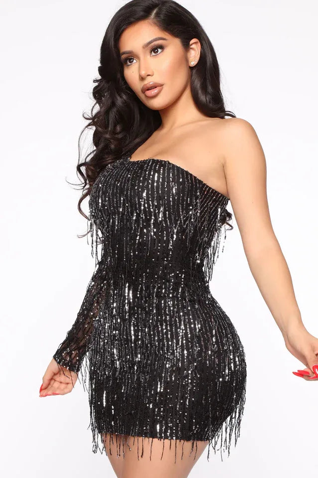 Close-up of a woman wearing a black sequined one-shoulder mini dress with fringe detail