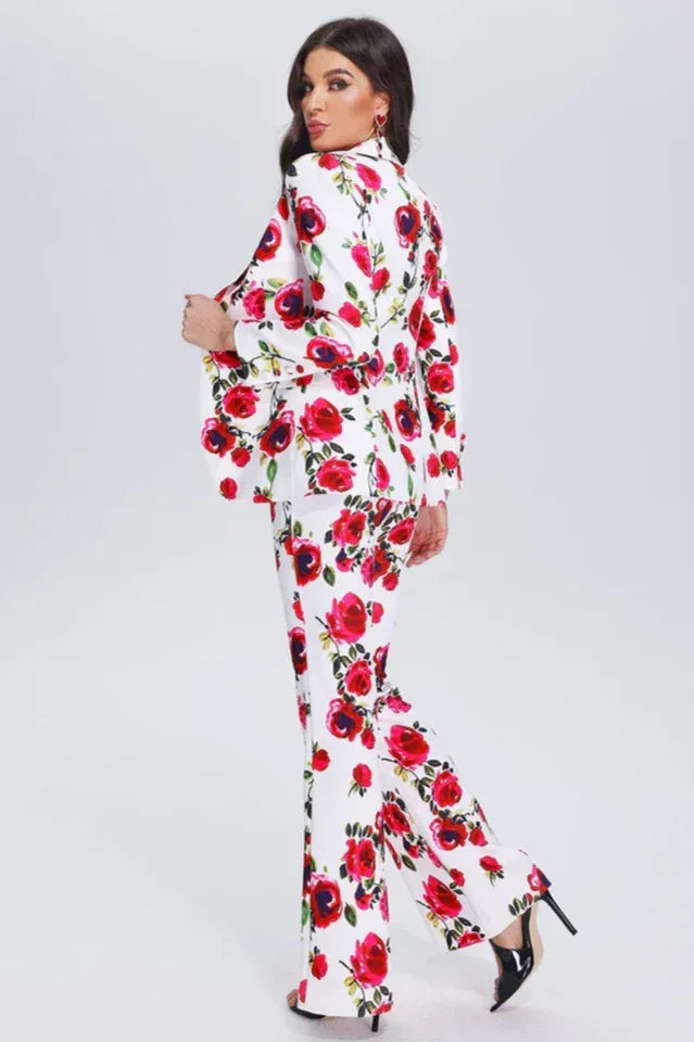 Woman wearing a white blazer and flared trousers with a red floral print, back view.