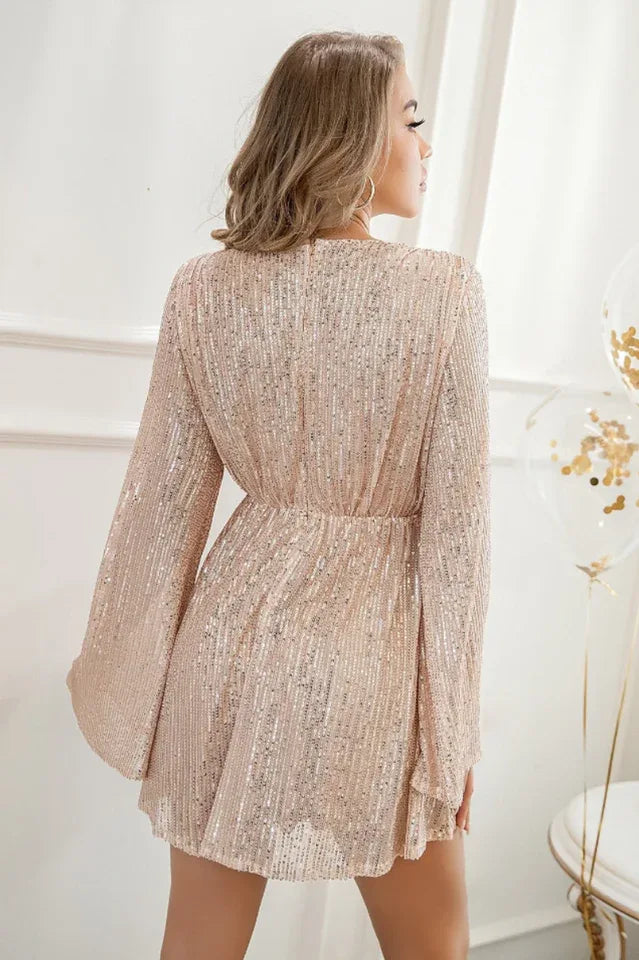 Back view of a woman in a rose gold sequin mini dress featuring bell sleeves and an empire waist.
