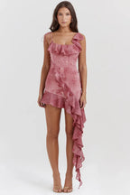 Full-body shot of a woman in a pink printed mini dress with a cascading ruffle.