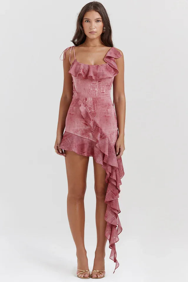 Full-body shot of a woman in a pink printed mini dress with a cascading ruffle.