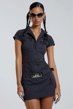 Model wearing a dark grey short-sleeve collared cargo dress with a silver buckle belt.