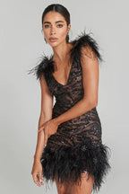 Woman wearing a short black sequined dress with feather accents on the shoulders and hem, featuring a plunging v-neckline.