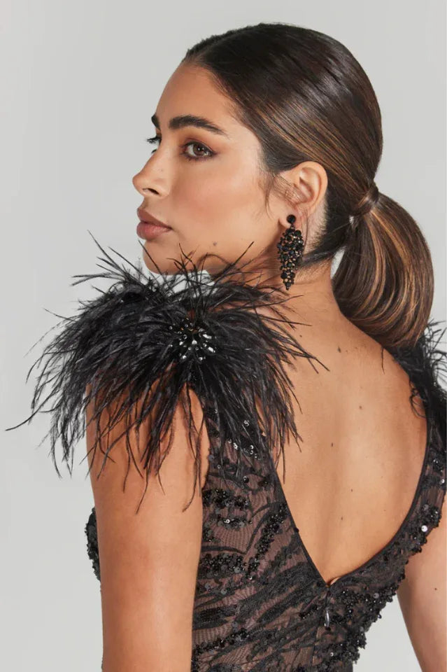 Close-up of the shoulder detail on a black sequined dress adorned with feathers.